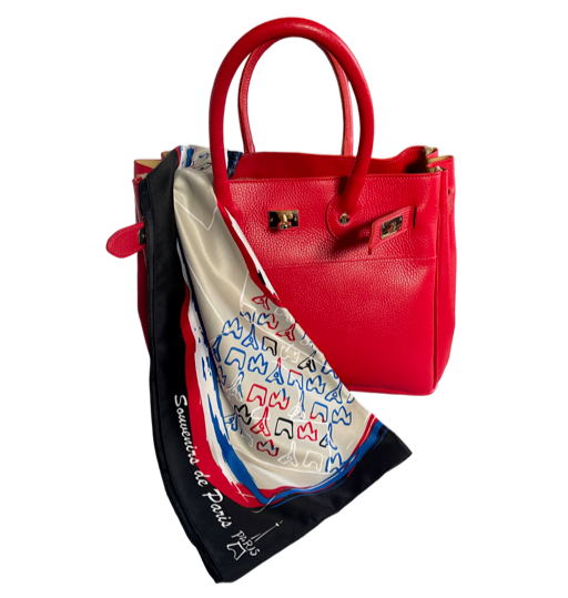 A red leather handbag with a Parisian scarf attached to it large enough for everyday.